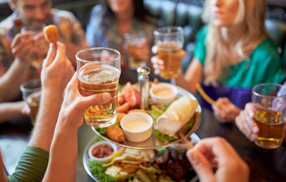 Happy Friends Eating and Drinking at Bar or Pub